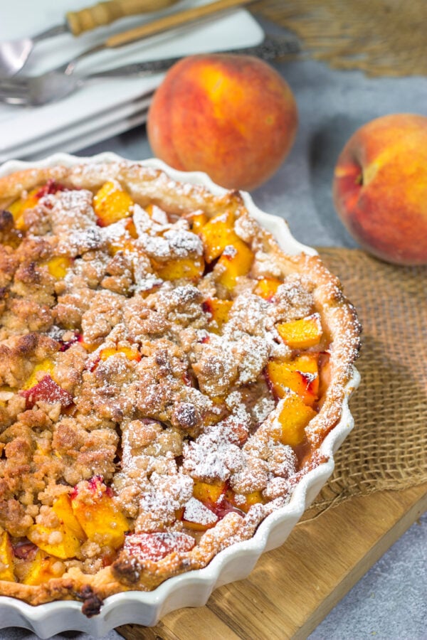 This Peach Crumble Pie features ripe peaches combined with brown sugar and nutmeg. The filling goes on top of a flaky, buttery crust and then a cinnamon sugar crumble gets sprinkled on top. Add a scoop of vanilla ice cream for the perfect summer dessert!