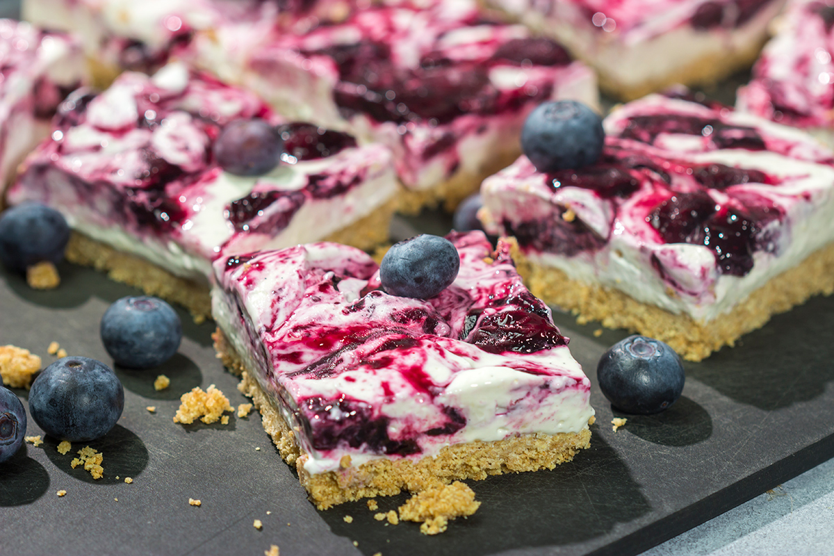 These No Bake Blueberry Cheesecake Bars feature a creamy cheesecake filling swirled with fresh blueberry jam on top of a buttery graham cracker crust. They're perfect for a hot summer day!