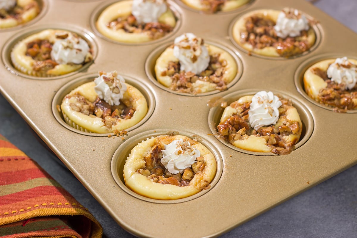 These Mini Pecan Pie Cheesecakes combine creamy cheesecake with crunchy pecan pie topping. This bite-sized dessert is perfect for holiday gatherings!