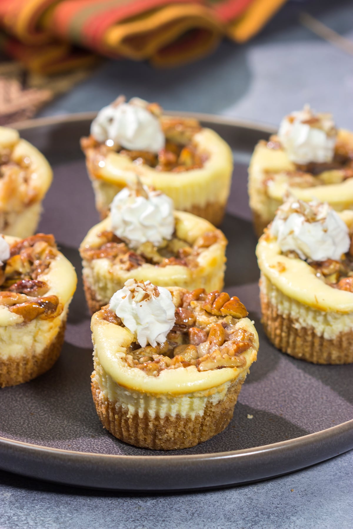 These Mini Pecan Pie Cheesecakes combine creamy cheesecake with crunchy pecan pie topping. This bite-sized dessert is perfect for holiday gatherings!