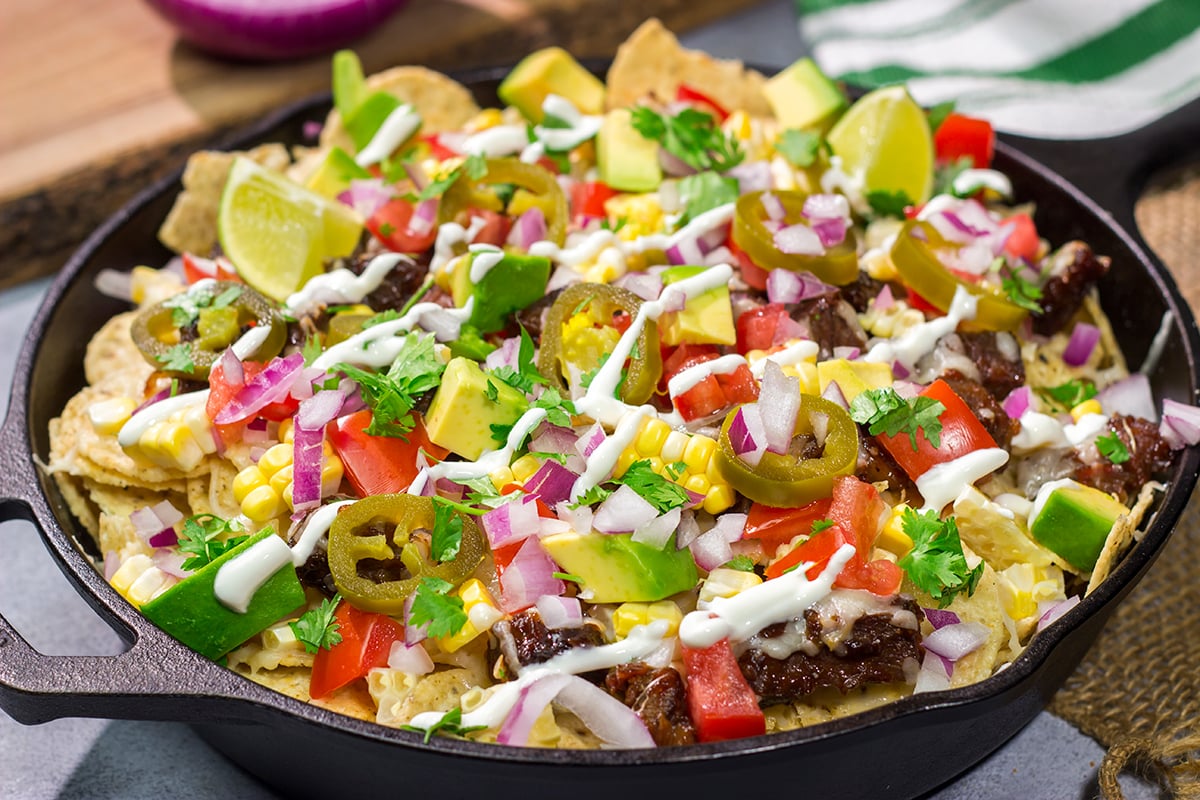 These Smoked Brisket Nachos are a great gameday appetizer! Crunchy tortilla chips topped with shredded cheese, smoked brisket and your favorite nacho toppings...yum!