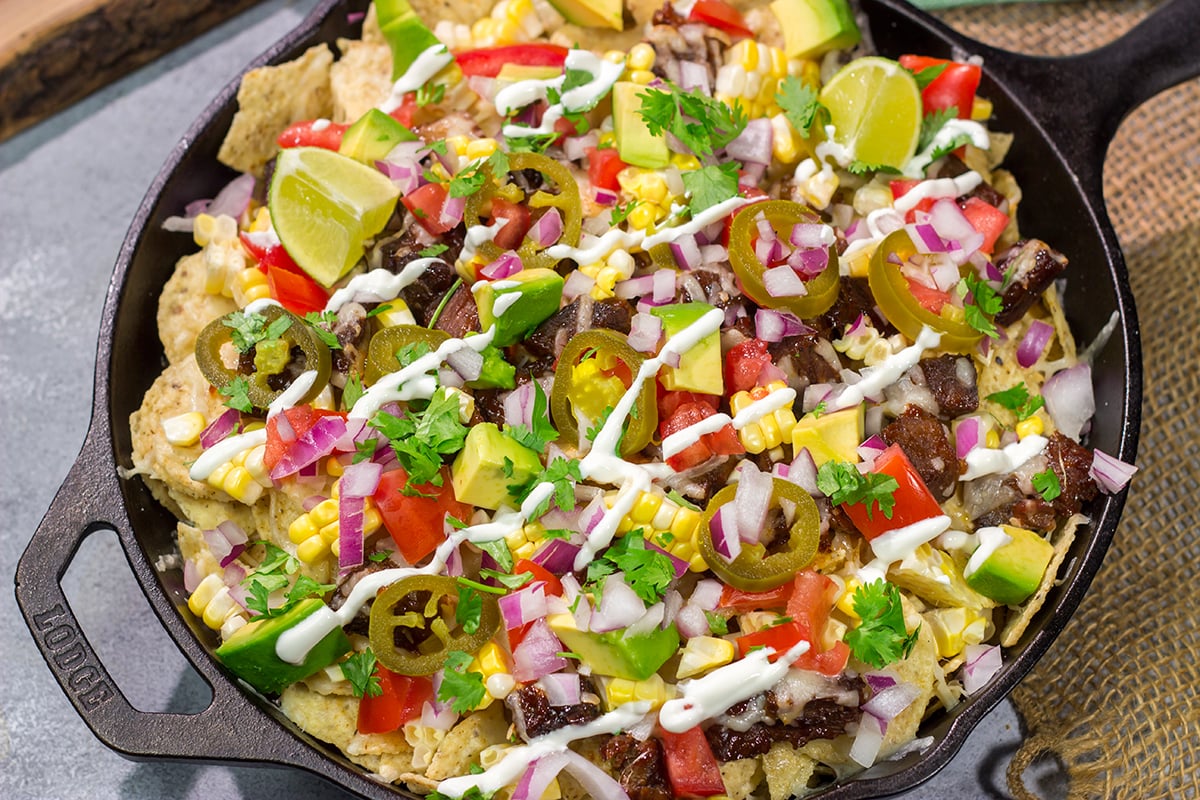 These Smoked Brisket Nachos are a great gameday appetizer! Crunchy tortilla chips topped with shredded cheese, smoked brisket and your favorite nacho toppings...yum!
