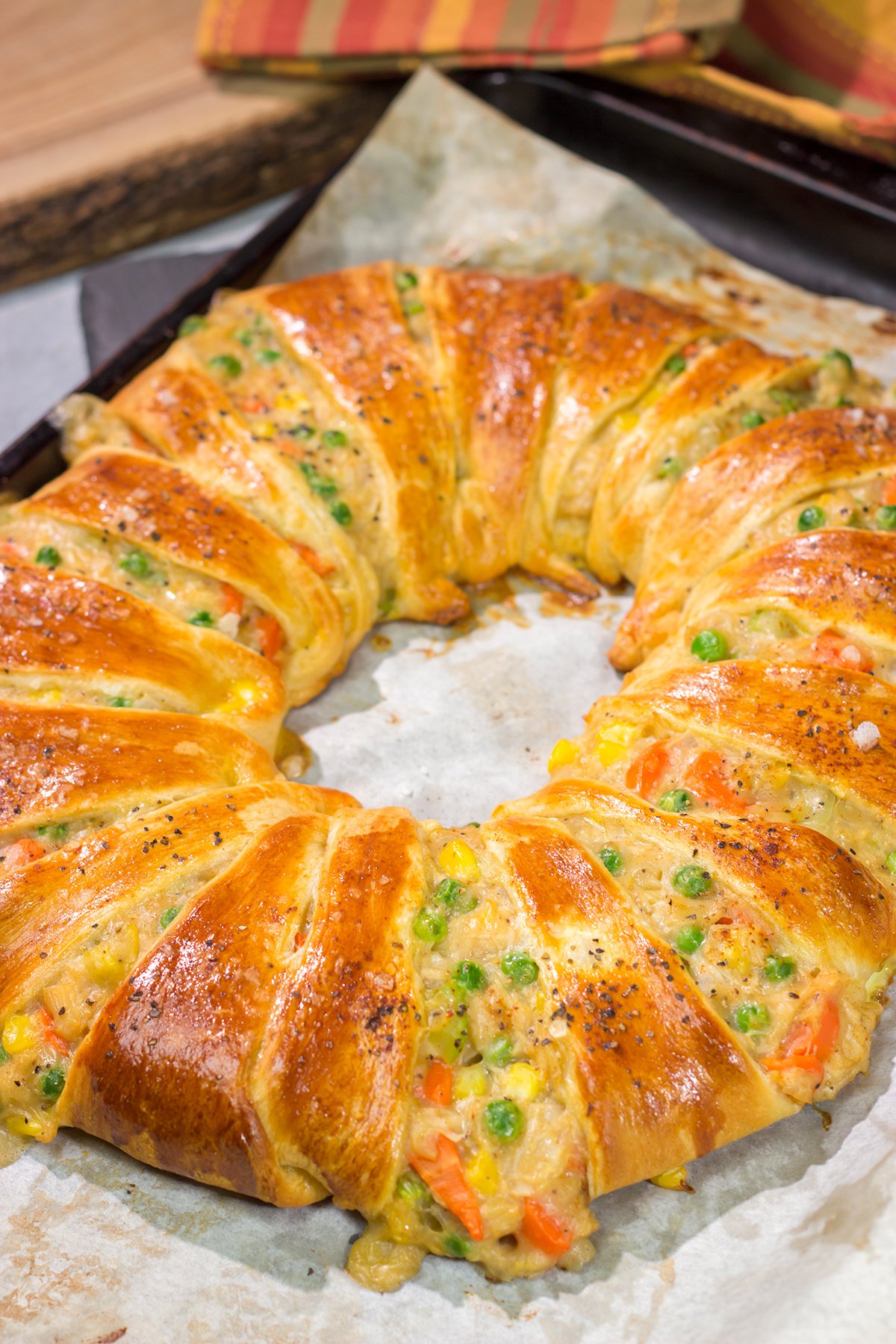 Put a unique spin on dinner with this Chicken Pot Pie Wreath! Homemade pot pie filling is wrapped in flaky crescent dough and shaped into a wreath for a fun take on a classic comfort food meal!