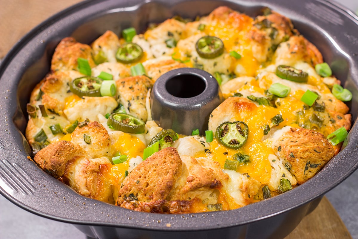 A warm loaf of this Jalapeno Cheddar Monkey Bread will be an instant favorite! This bread combines gooey melted cheese with fresh herbs and diced jalapenos - it's the ultimate comfort food.