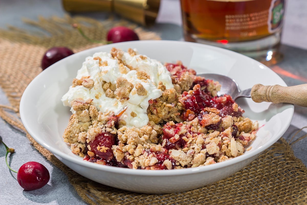 This Homemade Cherry Crisp is a simple dessert that the whole family will love. The homemade cherry filling gets topped with a crispy oat streusel...and a dollop of bourbon whipped cream!
